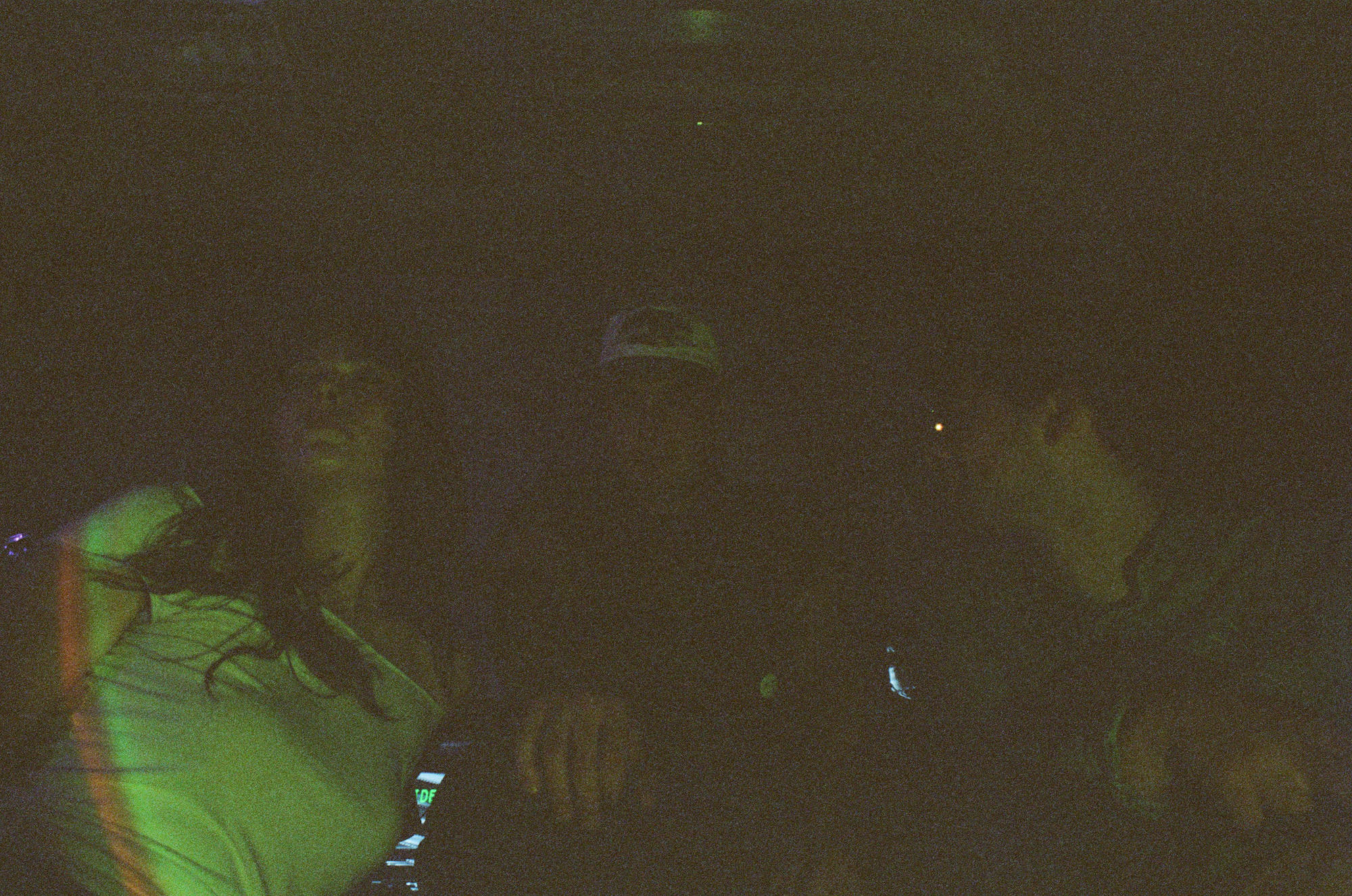 A grainy, green-lit view of a musician performing on a dark stage